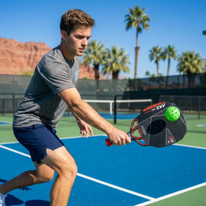 Man playing paddleball on a court with palm trees in the background with KOBO Thunder AXE Infinity paddle on hand doing a backhand drive.